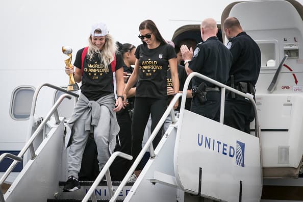 Julie Ertz y Alex Morgan, entre aplausos, bajan del avión que las trae a casa desde Francia, donde se celebró el Mundial de Fútbol.