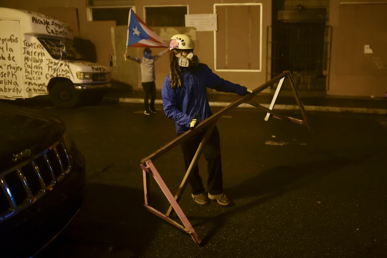 Un manifestante carga una valla durante la protesta en Viejo San Juan. Miles de personas se unieron a la protesta convocada por René Pérez "Residente" en repudio a la administración a la administración de la gobernadora Wanda Vázquez y por el mal manejo de suministros.