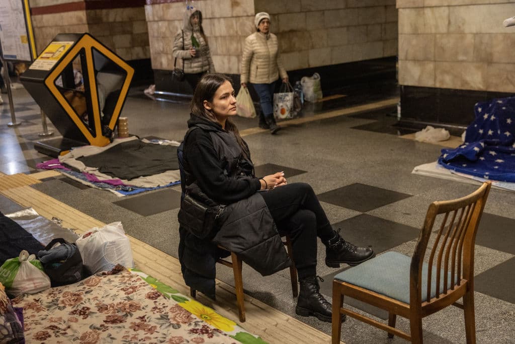 Una mujer sentada en una estación de tren en Kiev, convertida en refugio. Decenas de personas siguen escondidas en estos espacios mientras las fuerzas rusas permanecen en las márgenes de Kiev, una ciudad que quieren conquistar.