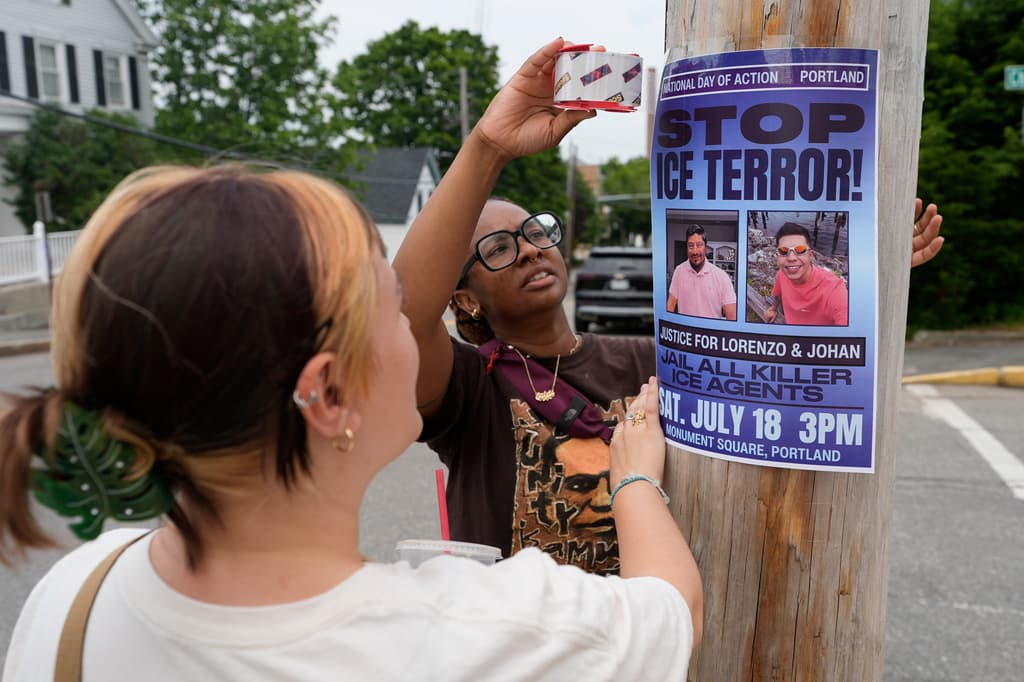 Angeliki Cintron (izquierda) y Saidi Moseley colocan un aviso sobre una próxima concentración en respuesta a las recientes muertes causadas por agentes del ICE, en Biddeford, Maine, el miércoles 15 de julio de 2026. (Foto AP/Robert F. Bukaty)