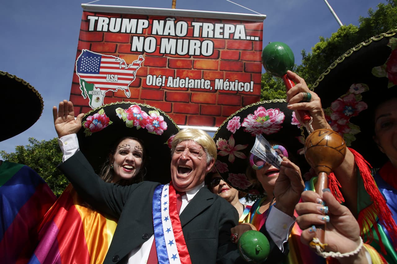 <b>Recife, Brasil. </b>Un personaje disfrazado de Donald Trump desfila junto a mujeres que llevan sombreros mexicanos con un cartel que dice en portugués “Trump no trepa… el muro”, en el carnaval de Recife, Brasil. 25 de febrero de 2017.