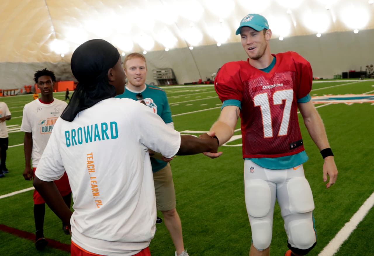 El quarterback de los Delfines de Miami (17) Ryan Tannehill saluda a un aficionado que acudió a presenciar el entrenamiento del equipo en sus instalaciones de práctica.