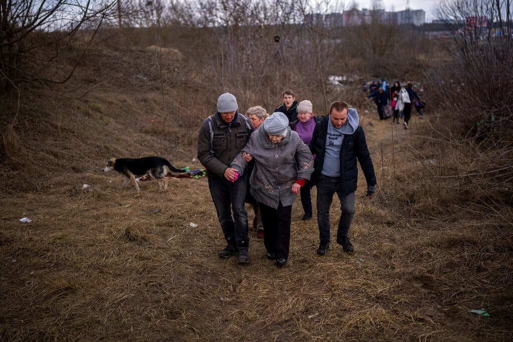 Gente huyendo de Irpin, a las afueras de Kiev, Ucrania, el lunes 7 de marzo de 2022, mientras se oye artillería cerca.