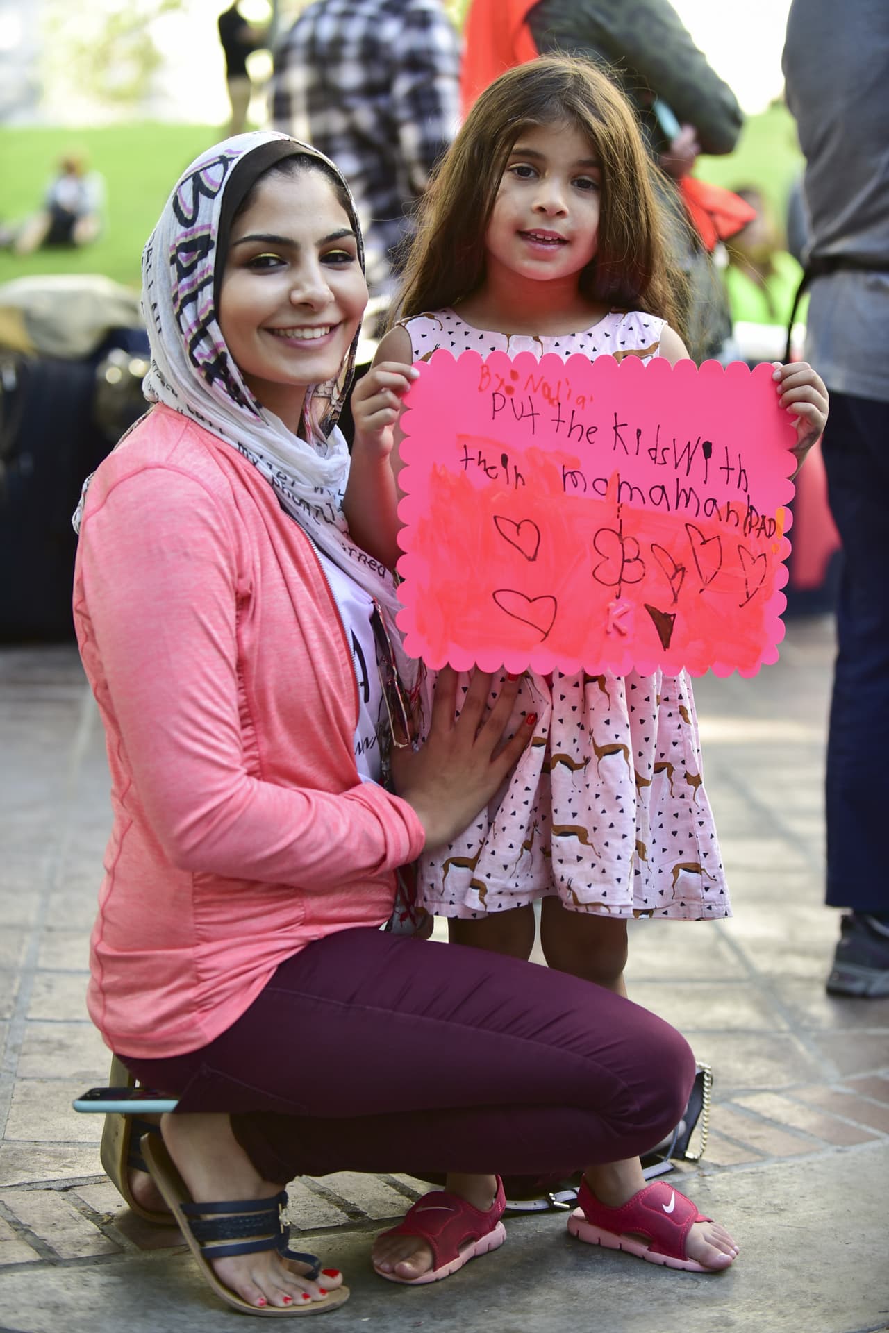 La niña sostiene un cartel con el mensaje "Lleven a los niños con su mamá y papá".