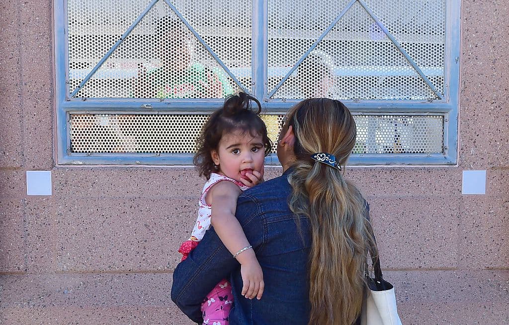 Una mujer con su hija en Nogales, Arizona, hablando con personas del otro lado del muro, en Sonora, México.