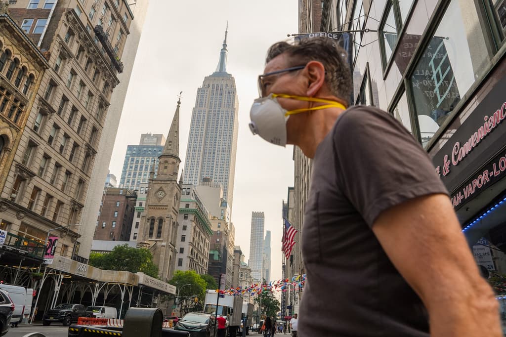 Una persona con mascarilla pasa frente al Empire State Building durante una alerta sanitaria por la calidad del aire debido al humo de incendios forestales, en Nueva York, el viernes 17 de julio de 2026. (Foto AP/Ryan Murphy)