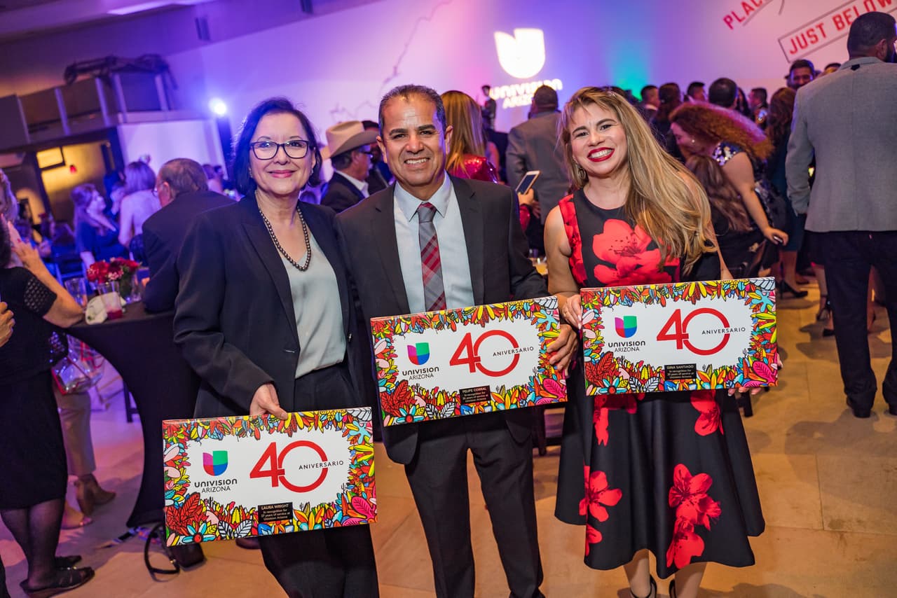 Laura Wright, Gina Santiago y Felipe Corral posan con su reconocimiento de servicio en Univison Arizona.