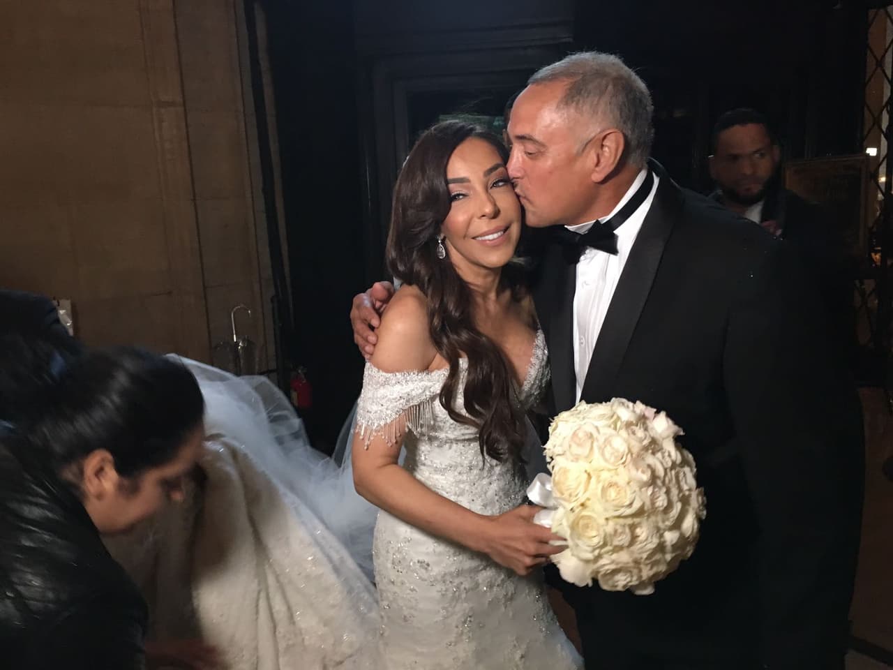 El papá de Gelena besa a la novia mientras unos ayudantes acomodan el velo de más de 5 metros de largo.