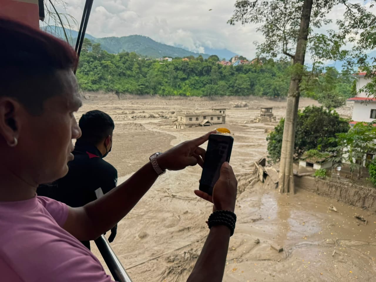 Varias personas toman fotografías y videos de las orillas crecidas y llenas de escombros del río Trishuli tras las inundaciones repentinas ocurridas en el distrito de Nuwakot, Nepal, el miércoles 26 de agosto de 2026