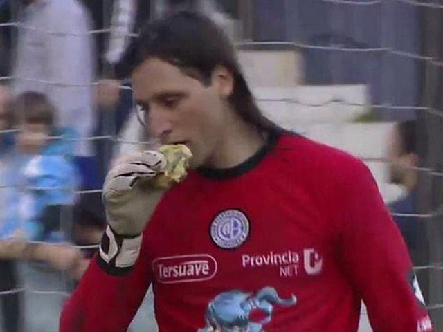 Portero argentino le da mordida a una hamburguesa que le arrojaron de la tribuna.