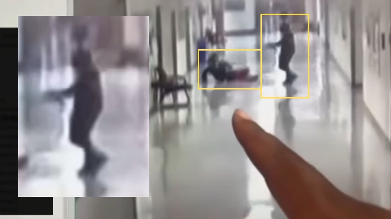 Nuevamente, la persona señala algo en la pantalla: esta vez, es
<b>el joven con la capucha acercándose con lo que parece ser un arma de fuego</b> al estudiante que permanece en el suelo.