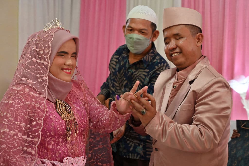 Wahyudi Rahmat (derecha) coloca un anillo de bodas en su novia Nuryani (izquierda) durante un matrimonio en masa para diez parejas con discapacidad visual en el día del palíndromo "22-2-22" en Bogor el 22 de febrero de 2022.