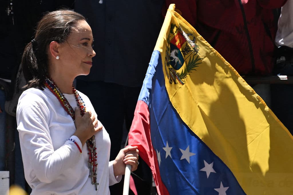 La líder opositora venezolana, María Corina Machado, sostiene una bandera mientras hace un gesto desde lo alto de un camión durante una manifestación para protestar por los resultados de las elecciones presidenciales, en Caracas el 3 de agosto de 2024, en los que el presidente Nicolás Maduro se declaró ganador, pero no ha mostrado las actas.