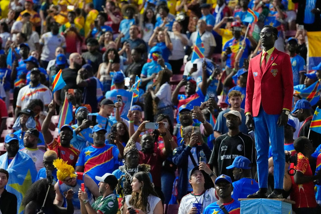 Michel Nkuka Mboladinga, simpatizante de la selección congoleña, posa junto a una estatua del héroe de la independencia asesinado, Patrice Lumumba, antes del partido de fútbol del Grupo K de la gesta mundialista entre Colombia y Congo en Zapopan, cerca de Guadalajara.