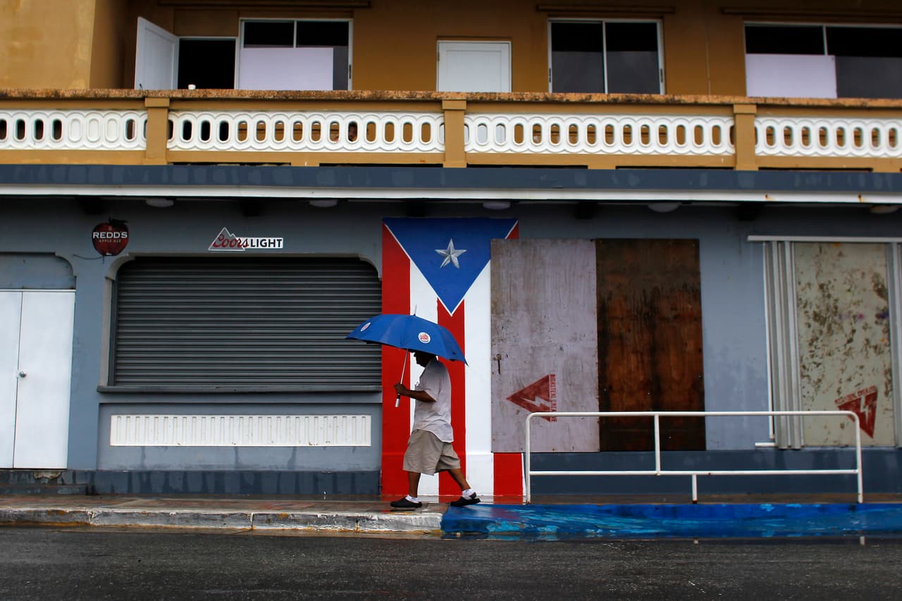 A man with an umbrella walks on a sidewalk as Hurricane Irma approaches Puerto Rico in Luquillo, on September 6, 2017. Irma is expected to reach the Virgin Islands and Puerto Rico by nightfall on September 6. / AFP PHOTO / Ricardo ARDUENGO (Photo credit should read RICARDO ARDUENGO/AFP/Getty Images)