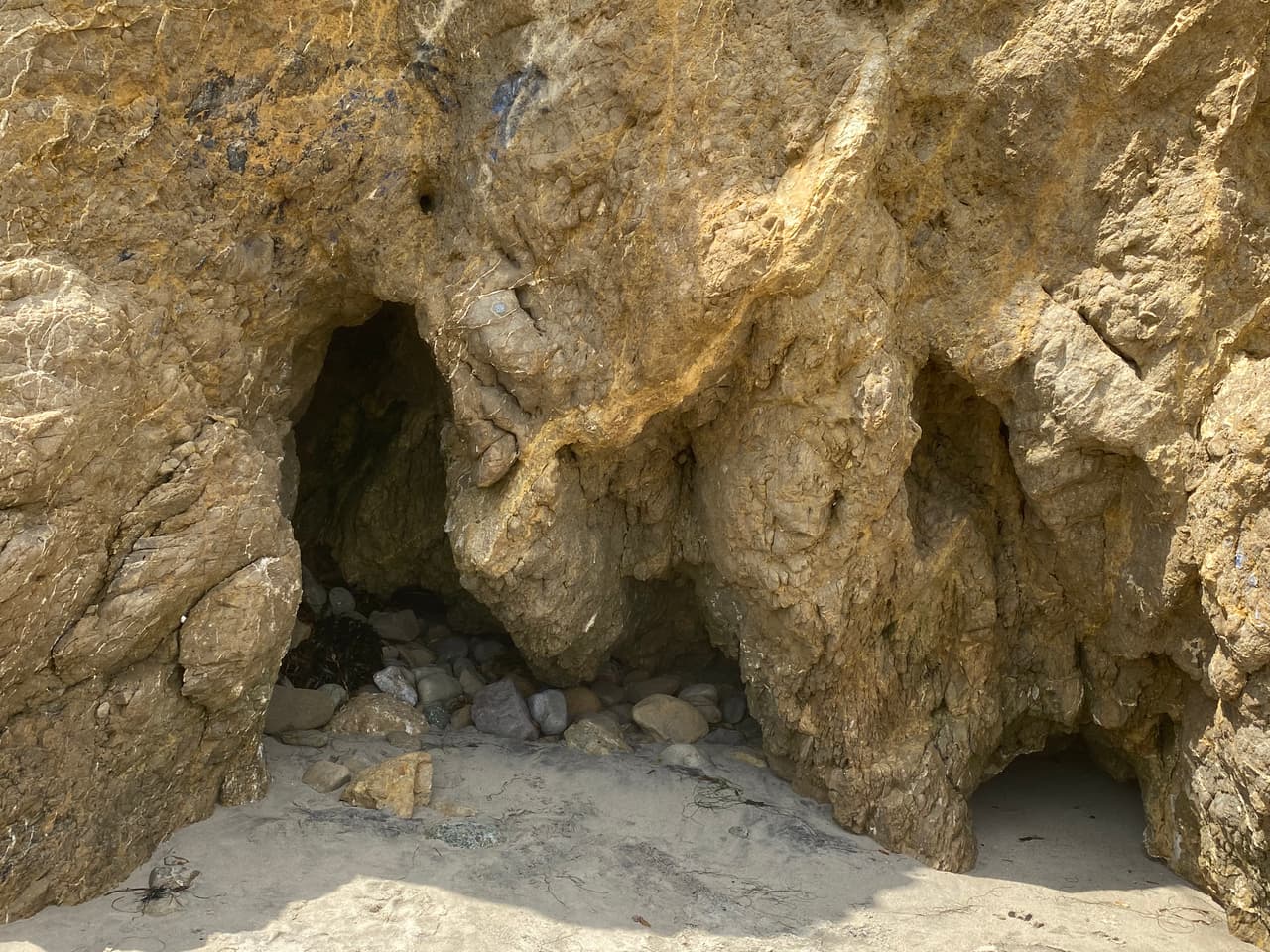 La cueva en medio del banco de arena a la orilla del mar no es la única, al norte de la playa encontrará otras formaciones en la base del acantilado.