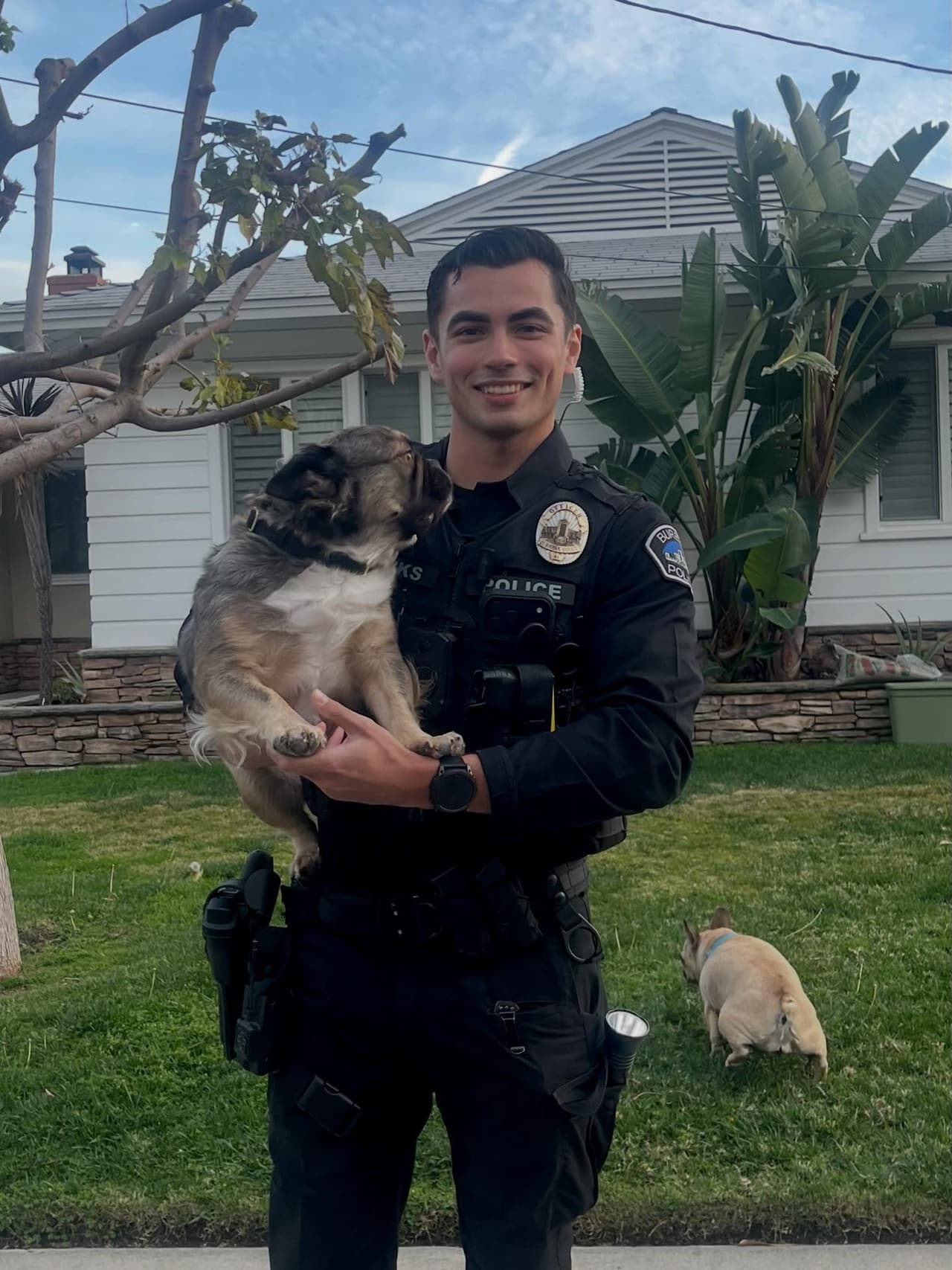 El Oficial Parks de la Policía de Burbank posa con un French Bulldog durante una llamada de servicio. La imagen se volvió viral en redes sociales, acumulando más de 240,000 likes y miles de comentarios coquetos.