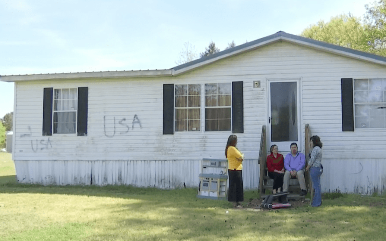 María Luisa Hernández y su familia se sientan frente a la casa que fue vandalizada.