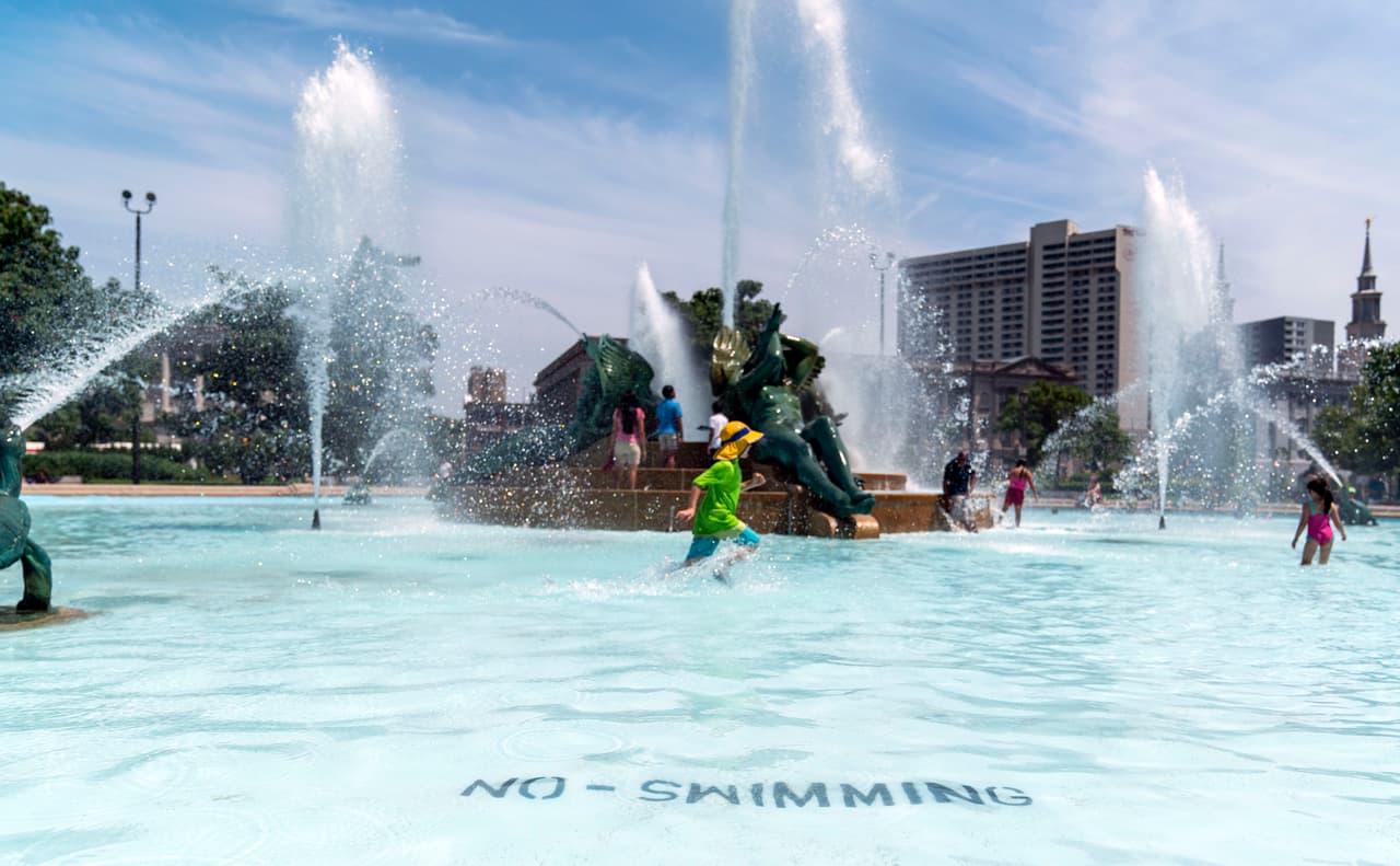 Niños juguetean con el agua de una fuente ubicada en el centro de la ciudad.