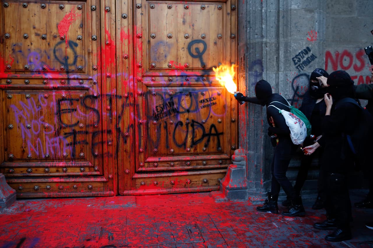 Manifestantes feministas se concentraron en la puerta del Palacio Nacional, y lanzaron globos de pintura roja contra las puertas durante una protesta contra los feminicidios en México.