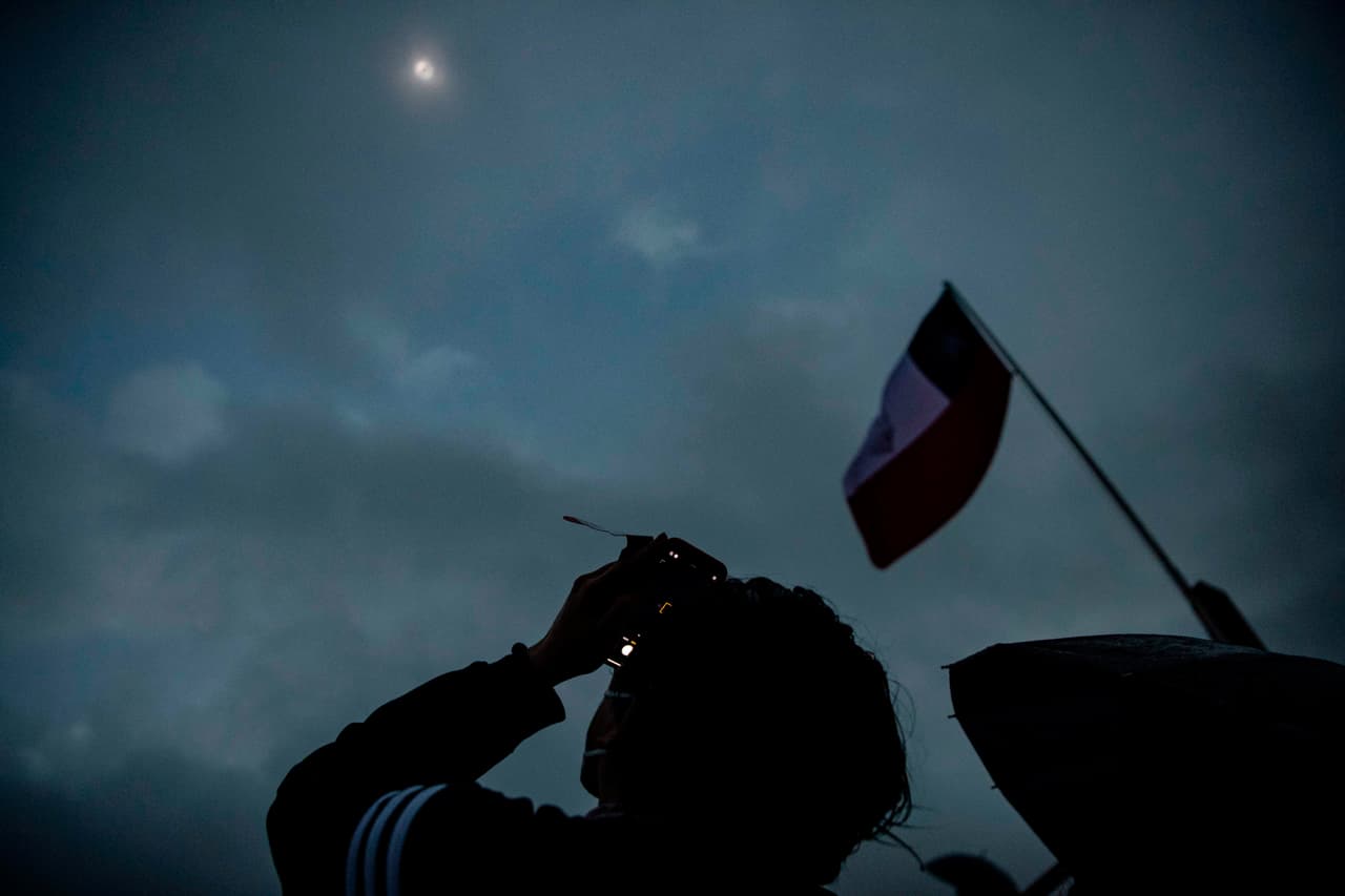 Un hombre toma fotografías del eclipse total de sol en Pucón, Chile, en medio de las nubes y lluvia que entorpeció la visibilidad del fenómeno.
<br>
<br>Fue descrito por la NASA como una "coincidencia celestial", oscureciendo a Chile y Argentina en pleno día.