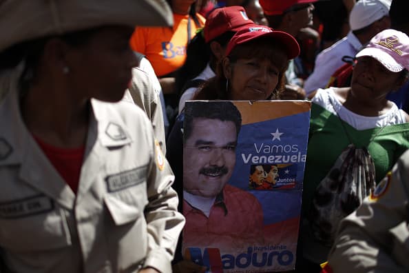 A demonstrator holds a poster with the image of President Nicolas Maduro during a pro-government rally in Caracas, Venezuela, on Wednesday, Jan. 23, 2019. President Donald Trump recognized Juan Guaido as the interim president of Venezuela minutes after the opposition leader declared himself the head of state, in the U.S.'s most provocative move yet against the leftist regime of Maduro. Photographer: Marco Bello/Bloomberg via Getty Images