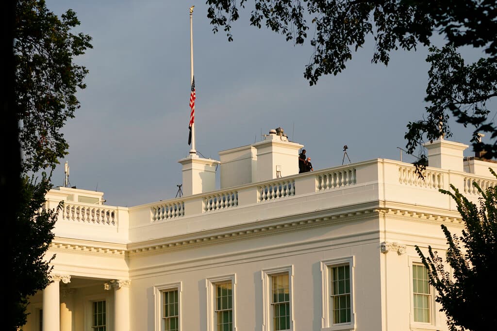 Los trabajadores caminan sobre el techo de la Casa Blanca en Washington, el jueves 26 de agosto de 2021, después de bajar la bandera a media asta para rendir homenaje a los miembros del servicio estadounidense y otras víctimas que murieron en el ataque terrorista en Kabul, Afganistán.
