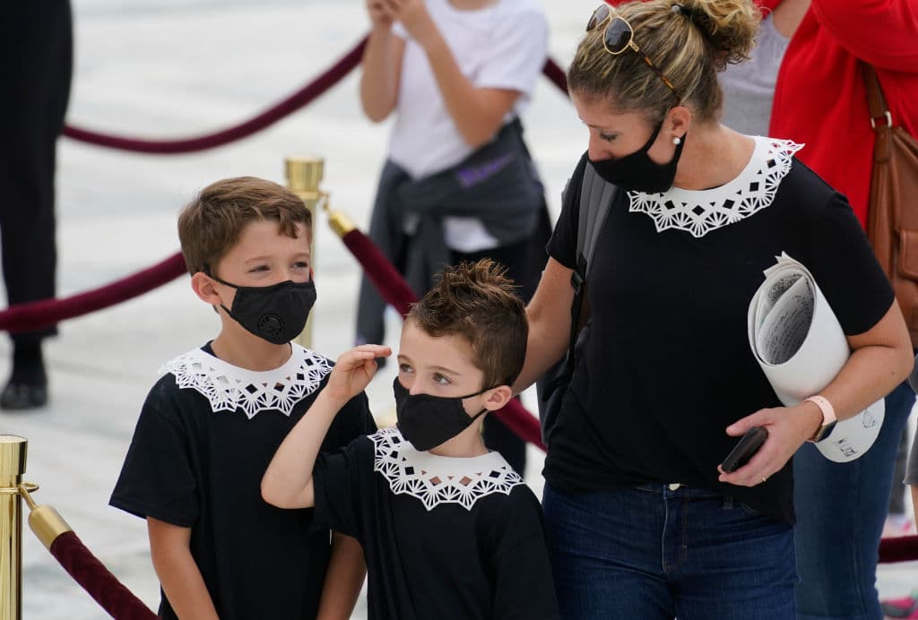 Una madre con sus hijos ante el edifico de la Corte Suprema presenta sus respetos a Ruth Bader Ginsburg.