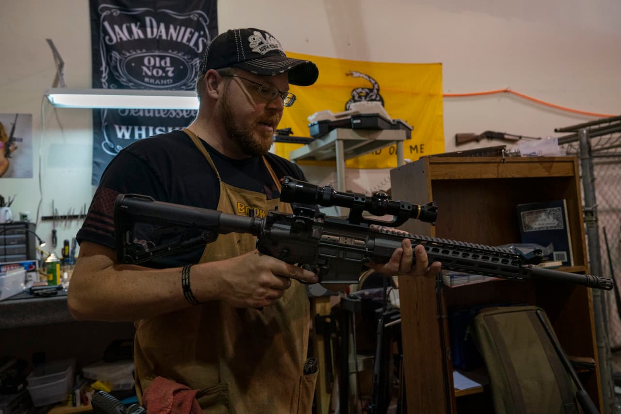 Jon Bush, un armero en Vancouver, WA, sostiene un AR-15 en su tienda. Bush dice que la popularidad del AR-15 tiene mucho que ver con la apariencia del rifle.