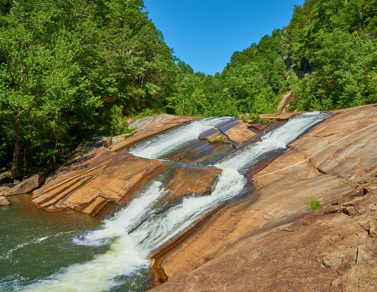 <b>Georgia.</b>
<br>
<br>Las Cascadas Bridal Veil, en el
<a href="https://gastateparks.org/TallulahGorge" target="_blank">Parque Estatal Tallulah Gorge de Georgia</a> son un enorme atractivo en verano. Pozos de agua y toboganes de piedra naturales hacen que sea atractivo para familias que escapan del calor. El parque advierte que cuando llega demasiada gente y el estacionamiento se llena al máximo, el personal del parque puede limitar temporalmente el acceso.