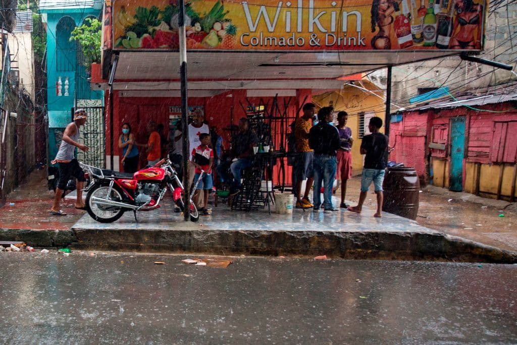 Varias personas se protegen de la lluvia en una tienda en Santo Domingo. La tormenta también provocó cortse en el suministro de agua que afectaron a más de 100,000 personas en la República Dominicana el sábado por la noche.