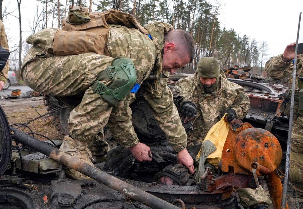 En la imagen, soldados ucranianos intentan sacar el cuerpo de un soldado ruso dentro de un tanque, en la villa de Dmytrivka, también cercana a Kiev.