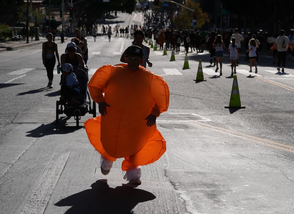Voluntarios distribuyeron materiales conmemorativos y coordinaron el flujo de participantes desde la línea de salida hasta la meta. El ambiente incluyó elementos de carnaval que contrastaron con el tráfico habitual del centro de la ciudad.
