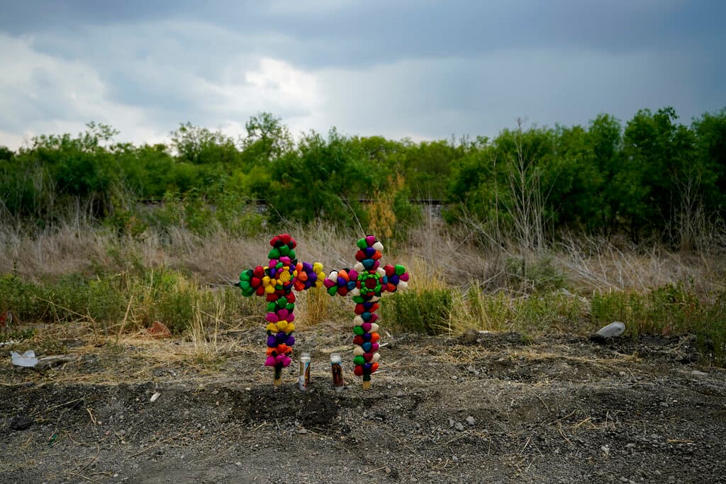 Cruces y velas marcan el sitio donde los funcionarios encontraron decenas de personas muertas en un semirremolque que transportaba a presuntos migrantes.
