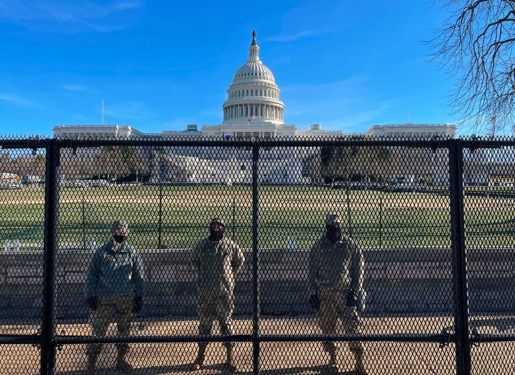 US National Guard soldiers guard the grounds of the US Capitol from behind a security fence in Washington, DC, on January 9, 2021.