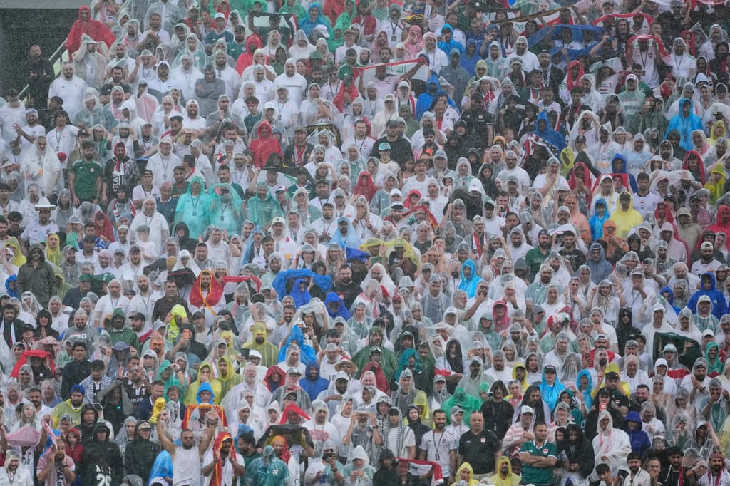 Los aficionados en la tribuna se protegen de la tormenta que comenzó a azotar en el estadio.
