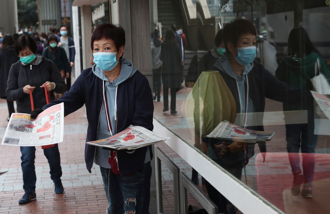Una mujer reparte tabloides con información sobre el coronavirus en Hong Kong este viernes.