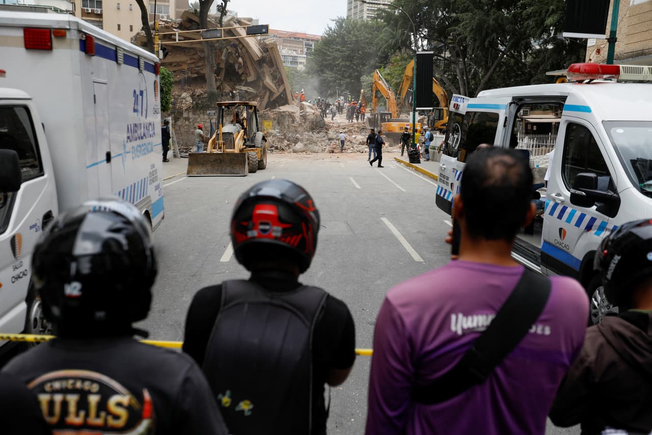 Varias personas observan cómo los servicios de emergencia trabajan en el lugar de un edificio derrumbado tras los terremotos que azotaron el país, en Caracas, Venezuela, el 25 de junio de 2026.