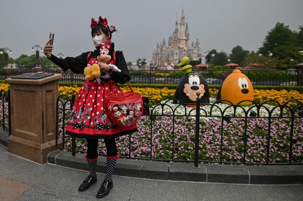 Una mujer con mascarilla en la entrada del parque temática en Shanghai.