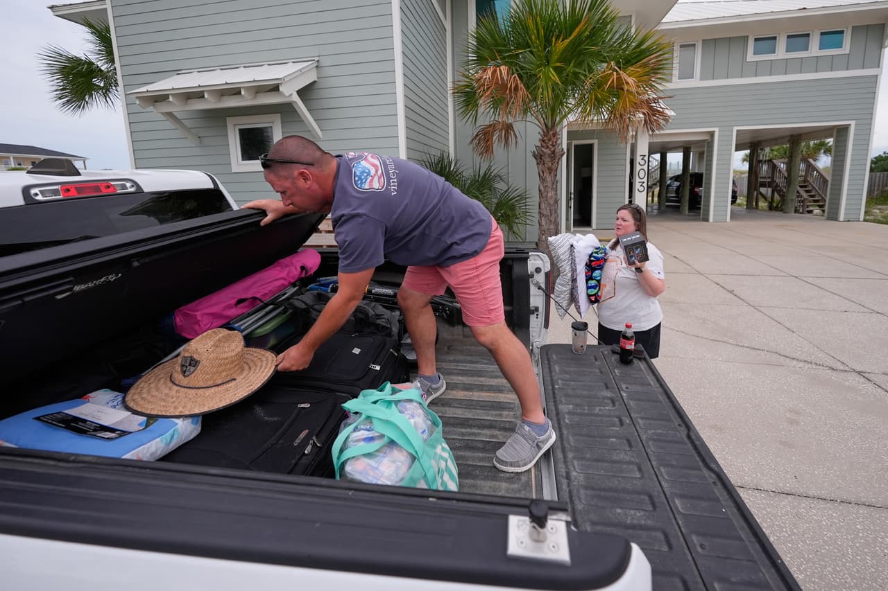 Daniel y Brand Harp, de Lebanon, Tennessee, que se encontraban de vacaciones, empacaron sus pertenencias para evacuar por la mañana ante la llegada del huracán Isaias a Pensacola Beach, Florida, el jueves 8 de octubre de 2026. (Foto AP/Gerald Herbert)