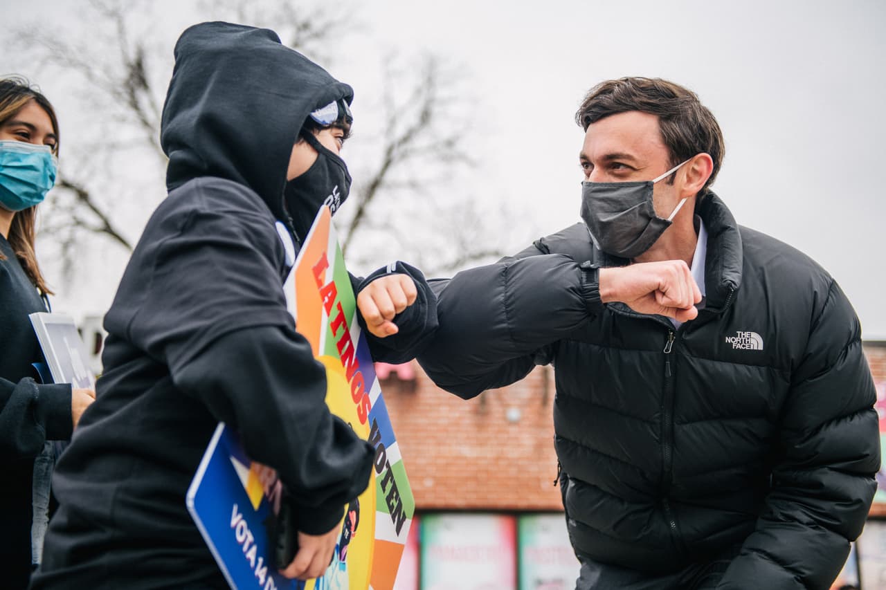 El candidato demócrata al Senado Jon Ossoff saluda con codo a un niño en una reunión de latinos y reunión de distribución de literatura el 30 de diciembre de 2020 en Marietta, Georgia.