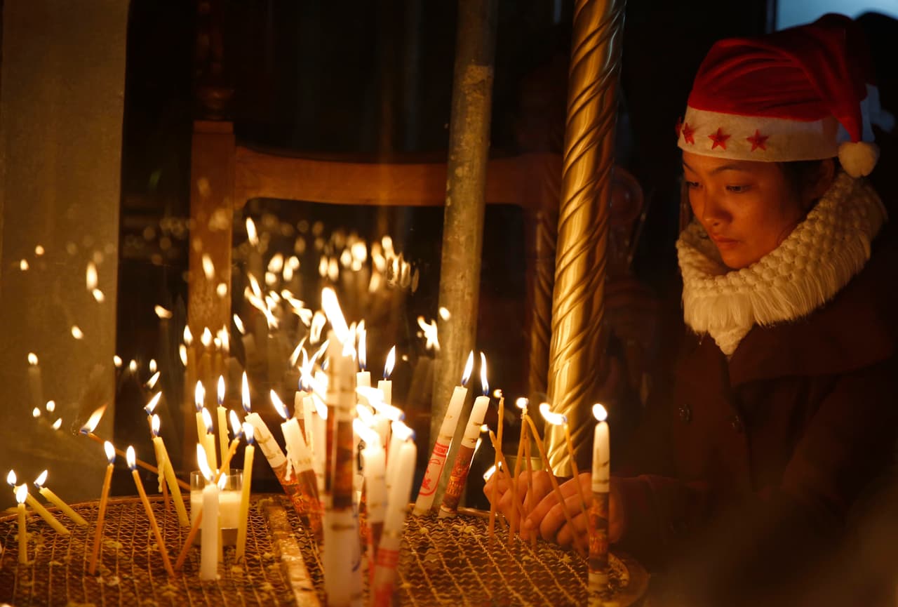 Una mujer enciende una vela en la iglesia de la Natividad, construida encima del sitio donde los cristianos creen que Jesucristo nació, en la ciudad de Cisjordania, Belén.