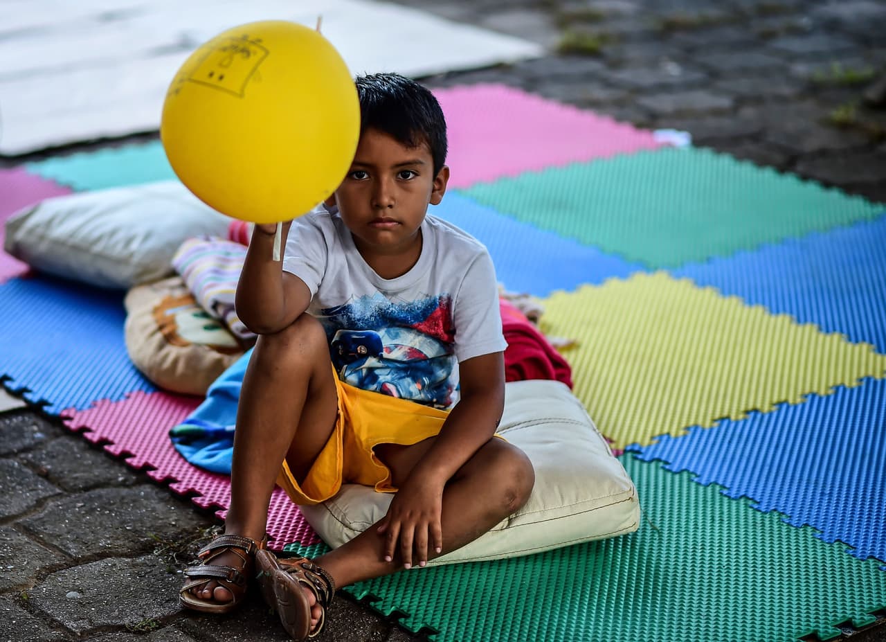 Un niño sostiene un globo mientras descansa en un refugio improvisado, en el poblado de Juchitán, Oaxaca.