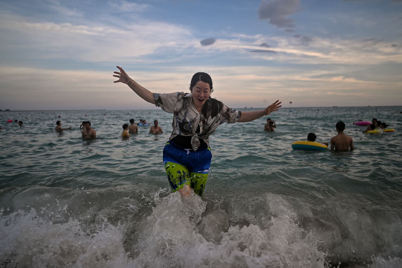 Los servicios esenciales tales como mercados y
<b>farmacias</b> están abiertos mientras que los sitios de entretenimiento han cerrado sus puertas. En la imagen, personas disfrutan de las playas de Sanya.
<br>
<br>