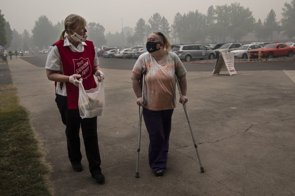 <br>Mary Thomson, izquierda, de Phoenix recibe ayuda del oficial del Ejército de Salvación Tawnya Stumpf en el centro de evacuación establecido en el recinto ferial del condado de Jackson.