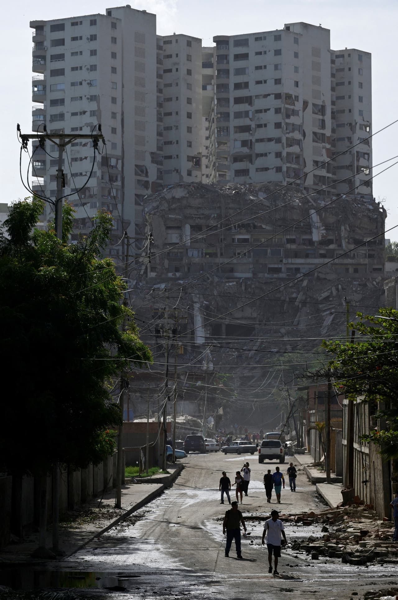 Personas caminan entre los escombros de edificios dañados tras los terremotos en La Guaira, Venezuela, 25 de junio de 2026.