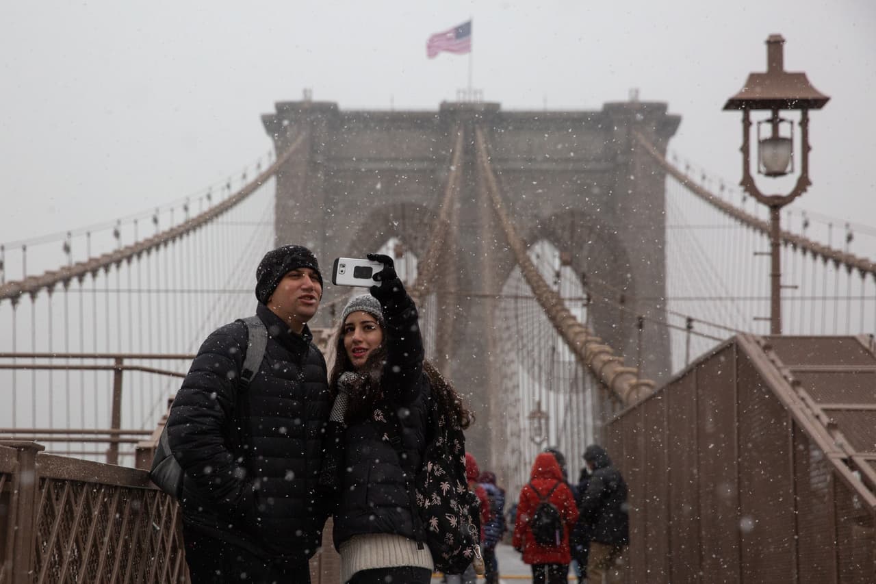 Turismo helado sobre el puente de Brooklyn. Nueva York experimentó su primera nevada de la temporada. Más de una pulgada de nieve podría caer en el área.