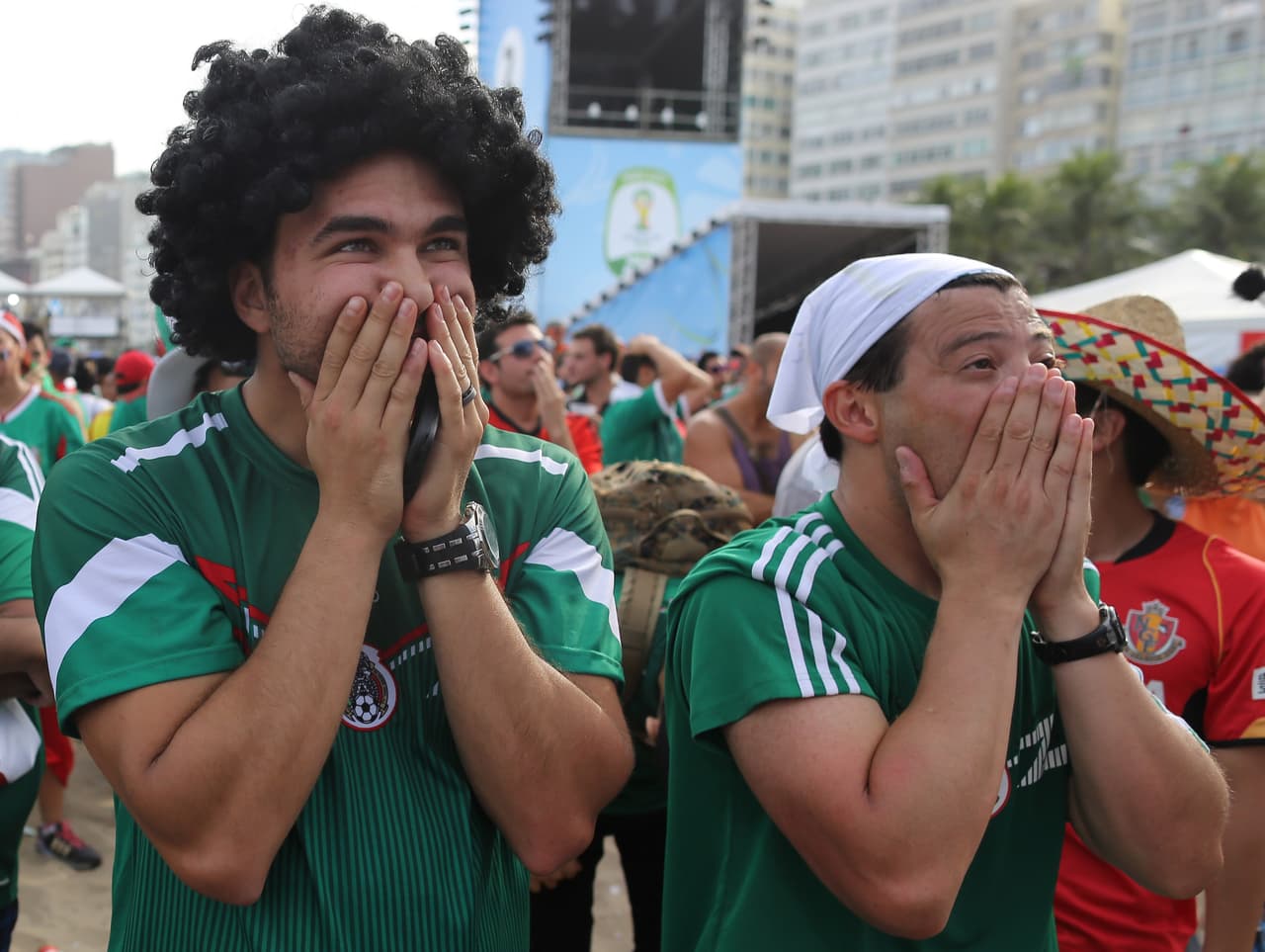 Aficionados mexicanos reaccionan tras el segundo gol en contra de su selección mientras ven el partido de octavos de final del Mundial contra Países Bajos en directo desde la zona del FIFA Fan Fest en la playa de Copacabana, Río de Janeiro, Brasil en 2014.