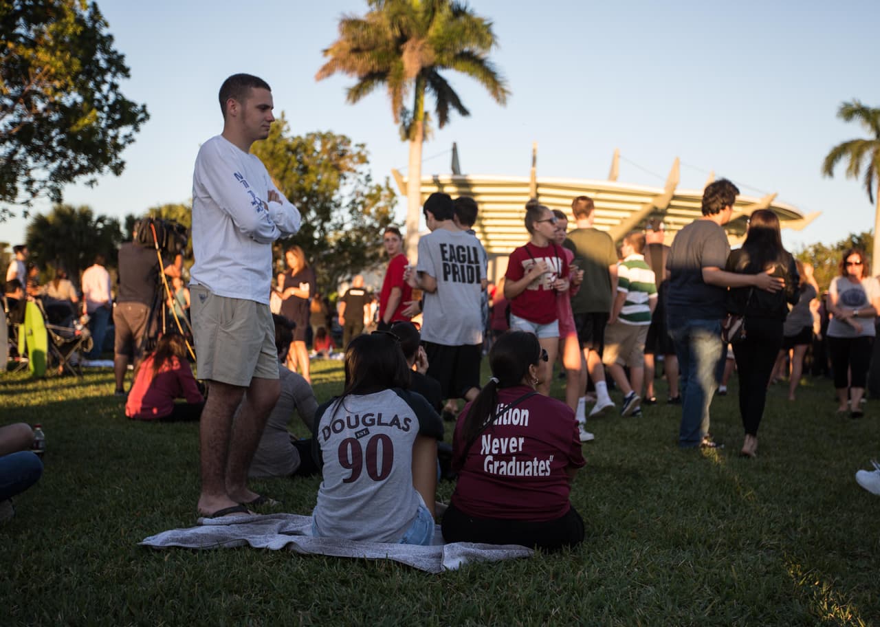 Sentadas; derecha: Laurie Portal, de Nueva York, y su hija Sarah Portal, quien se graduó hace 3 años de la escuela, decidieron ponerse camisetas de la escuela tiroteada para honrar a su hijo y hermano, superviviente del tiroteo quien perdió a amigos ayer. La madre lleva una camiseta del equipo de béisbol que un amigo de su hijo le regaló a su hijo; la hermana una camiseta obsequio de una de sus antiguas profesoras. "Necesitamos control de armas y restringir el acceso a los rifles semiautomáticos", dice Laurie, "pero si no pasó con los bebés de Sandy Hook no creo que pase ahora"