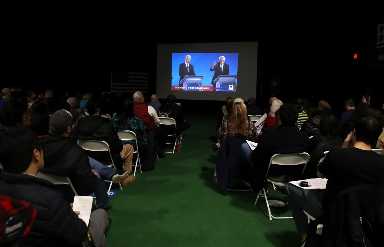 Grupo de personas mira el debate en un gimnasio de Manchester, New Hampshire.
